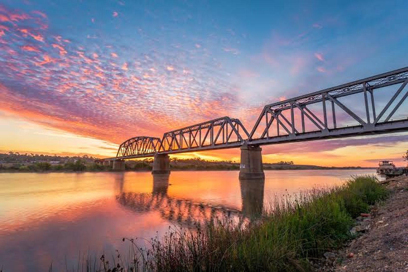 A pink and orange sunrise behind the Murray Bridge road bridge