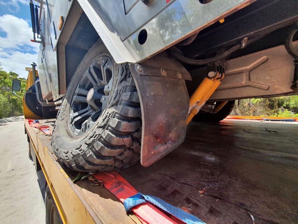 A damaged caravan wheel and suspension on a tow truck after a road incident